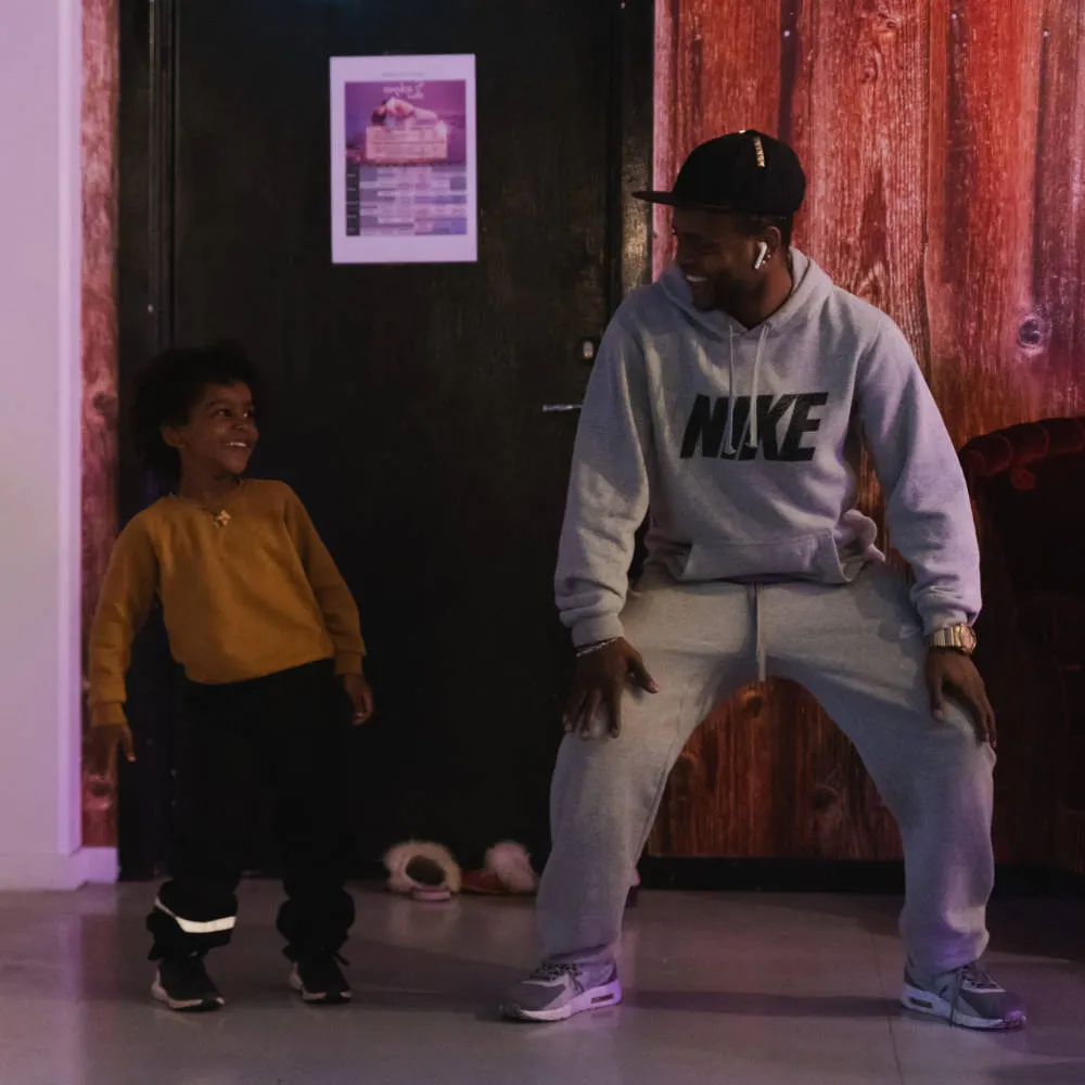 A hip hop instructor dancing in front of a young student