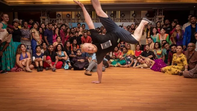 A breakdancer mid-move in front of a large crowd