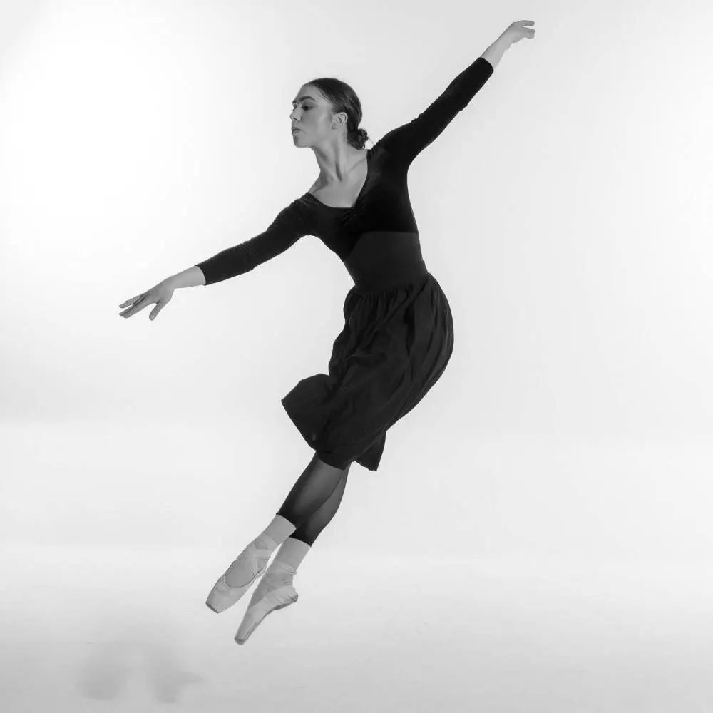A dancer leaping in a white studio