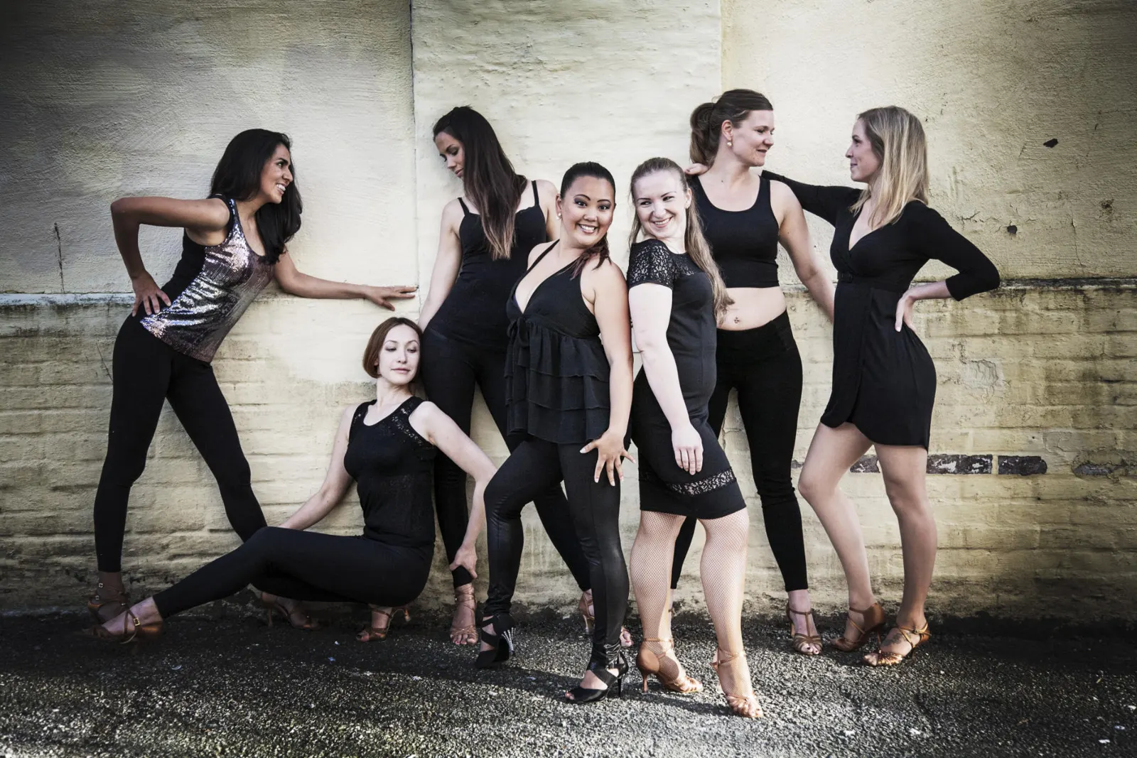 A group of dancers posing together against a white wall